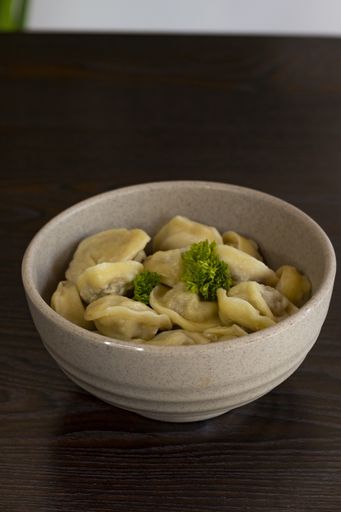 A vertical closeup shot of a bowl of traditional Russian dumplings