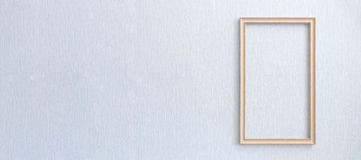 Beautiful frame for picture or photograph of beige color from wooden baguette hangs on light grunge wall.