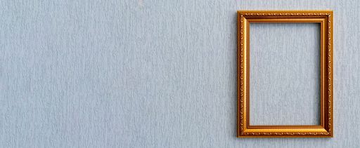 Beautiful frame for picture or photograph of gold color from wooden baguette hangs on light grunge wall.