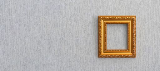Beautiful frame for picture or photograph of gold color from wooden baguette hangs on light grunge wall.