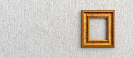 Beautiful frame for picture or photograph of gold color from wooden baguette hangs on light grunge wall.