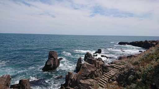 A beautiful view of rocks and stones by the sea under blue cloudy sky on the horizon