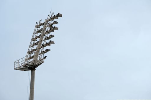 A low angle shot of tall stadium lights in a blue sky