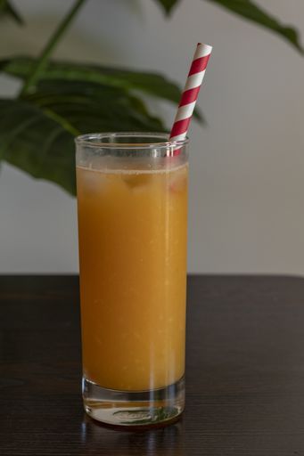 A vertical shot of a glass of orange juice and a paper straw