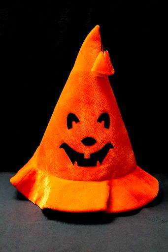 A vertical closeup shot of a carved pumpkin-shaped Halloween hat