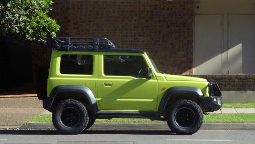 side view of lime green color two door jeep parked outdoors on street in front of building