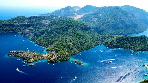 An aerial of sea cliffs and boats sailing along the coast