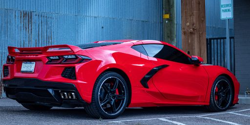 A luxurious red sports car parked in a parking lot in daylight