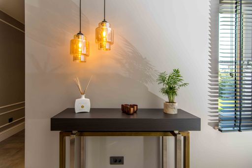 A beautiful white room, a plant and some incents on a nice and neat table with two lamps above