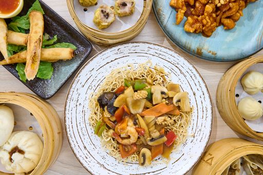 A closeup of crispy noodles stir fry with other dishes on a table. Chinese cuisine.