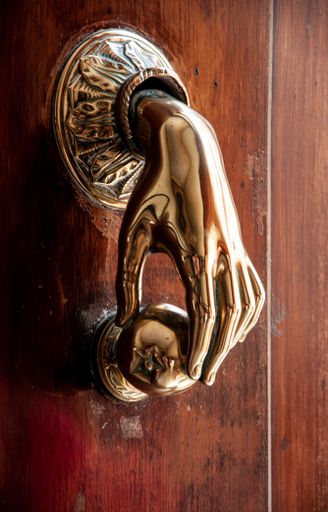 A closeup shot of the golden hand-shaped doorknob