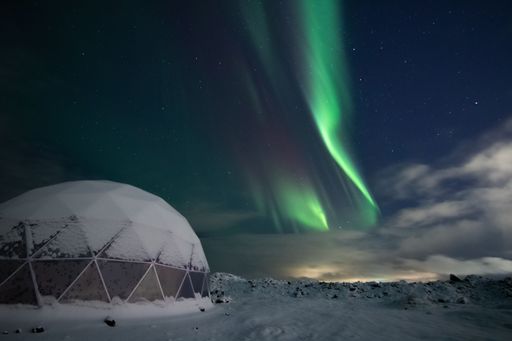 A modern igloo structure illuminated the northern lights.