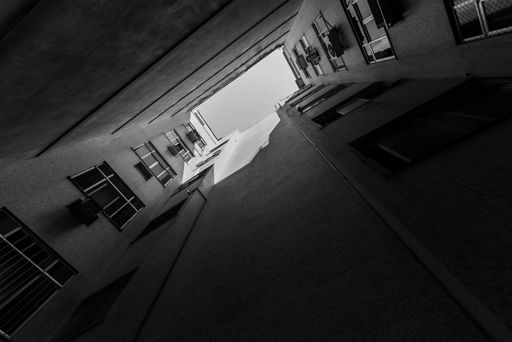 A low angle of a residential building in shadows and sunlight against the sky shot in grayscale