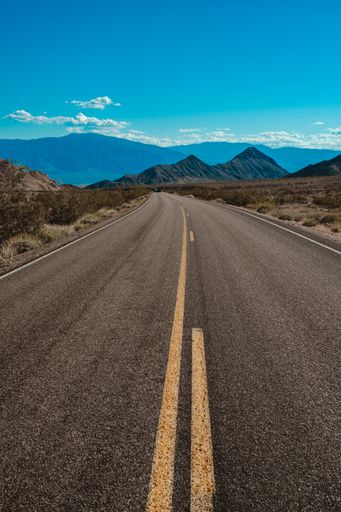 A vertical shot of a road in the desert under the beautiful blue sky captured in California