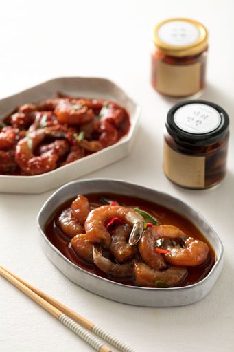 A vertical shot of shrimps in bowls with sauces on the side on a white table