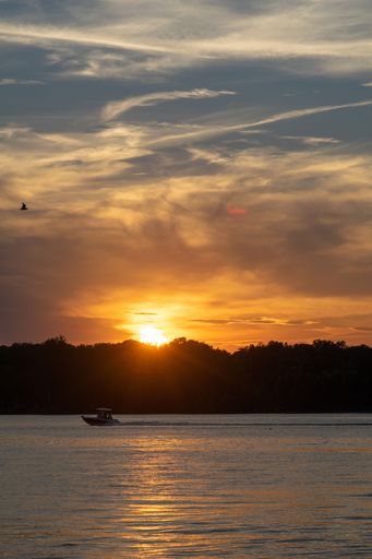 A vertical shot of scenic sunset over the lake with a boat on its surface