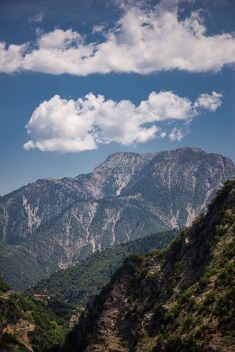 A vertical image of green covered mountains with beautiful sky during daytime
