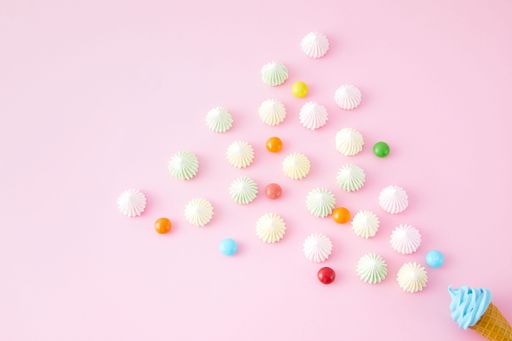 A Top view of swirled marshmallows, skittles and ice cream cones isolated on a pink background