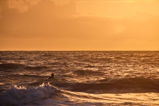 A beautiful shot of a man swimming in a sea during the golden hour