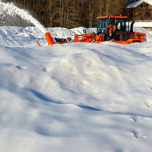 A red truck cleaning the snow from the street in a ski resort