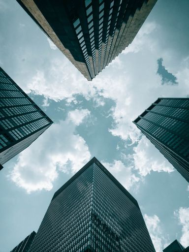 A vertical low angle shot of modern buildings with glass exterior against a beautiful cloudy sky