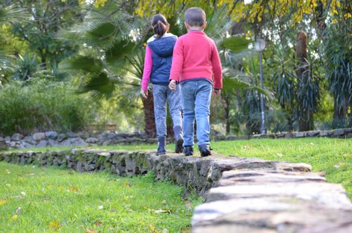 A long shot of two children walking over a stone path
