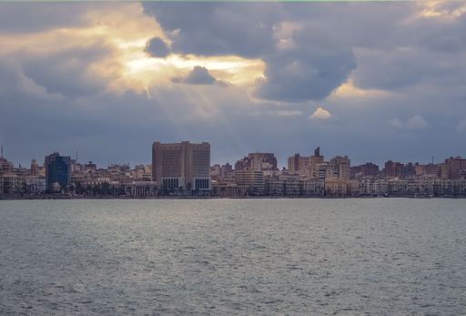 A beautiful shot of Alexandria cityscape with body of water in the foreground, cloudy sunrise
