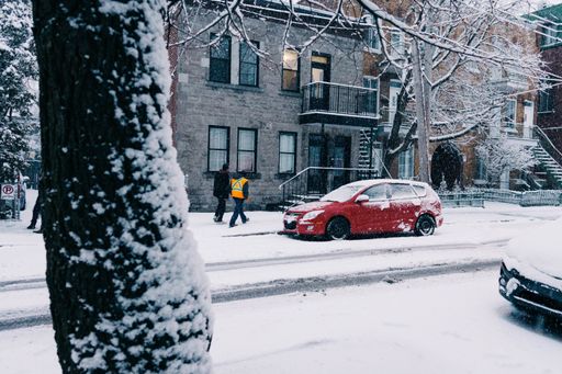 A beautiful shot of a snowy road with cars and people