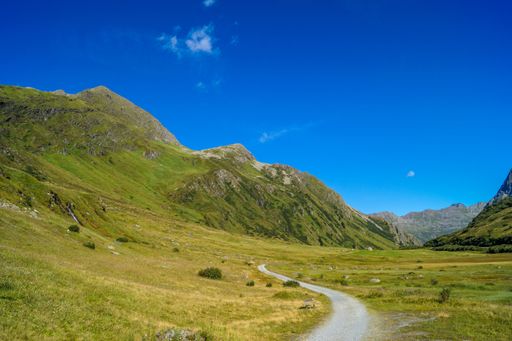 A scenic view of a path going through a valley surrounded by mountains