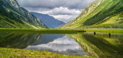 An alpine lake surrounded by green mountains. Silvretta High Alpine Road, Switzerland.
