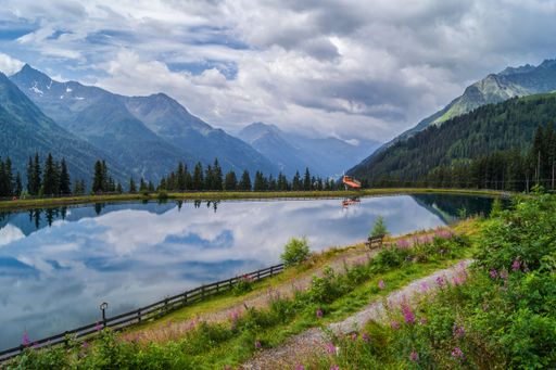An alpine lake surrounded by green trees and mountains. Silvretta High Alpine Road, Switzerland.