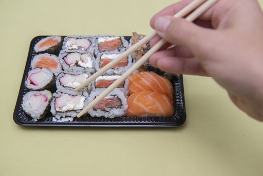 A closeup shot of assorted sushi with chopsticks on the table