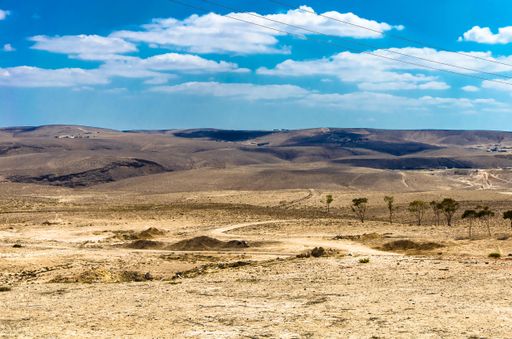 A wide dessert with a cloudy blue sky