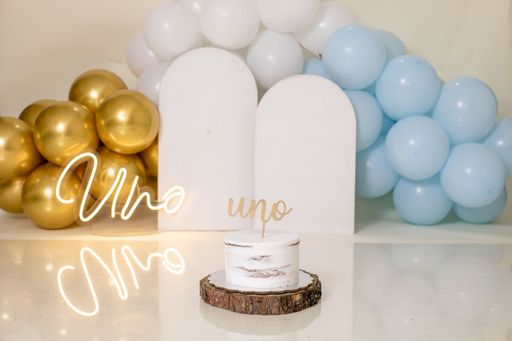 A closeup of a candle with an inscription against the background of colorful balloons.
