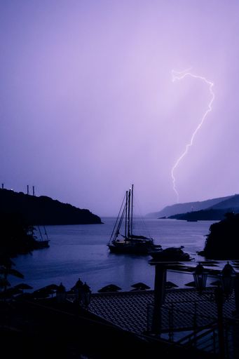 A huge lightning bolt that illuminates the sky purple. The photo was taken in Greece over Karvouno bay.