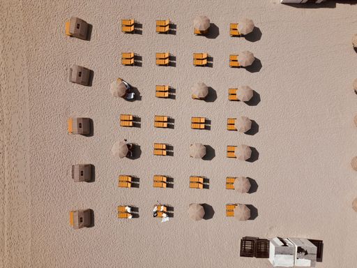 An aerial drone view of sunbeds and umbrellas on the beautiful sandy Miami beach on a sunny day