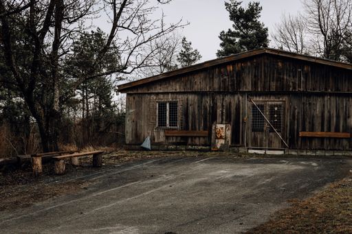 The facade of an old abandoned wooden building surrounded by trees in fall