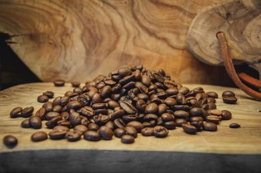 A pile of roasted coffee beans on a wooden board