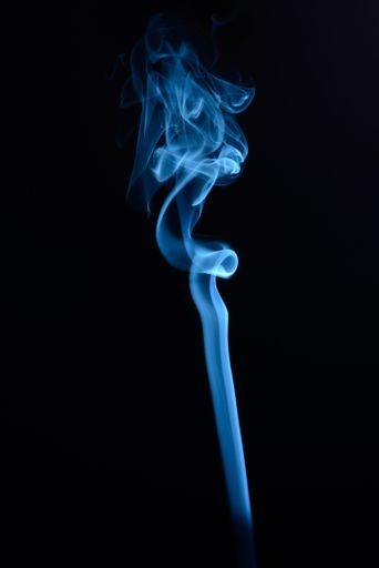 A vertical shot of blue tobacco smoke on a black background