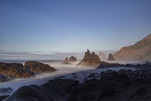 A breathtaking view of the mountains tops under the blue sky captured in a foggy weather