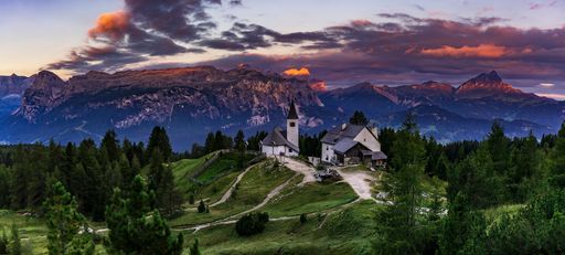 A fantastic view of buildings on a hill and the dolomite mountains in Badia, Italy during sunset