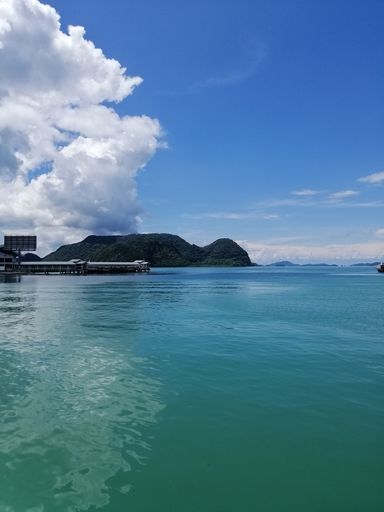 A cloudy sky on tranquil sea water with mountains on the horizon, vertical shot