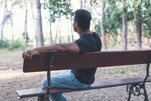 A shallow focus shot of a middle-aged male sitting on a park bench