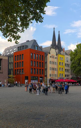 A vertical shot of the colorful buildings at Altermarkt in old town Cologne with the spires of Cologne Cathedral in the background