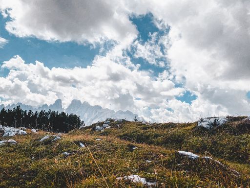 A beautiful view of a dry hillside with rocky mountains and fluffy clouds in the background