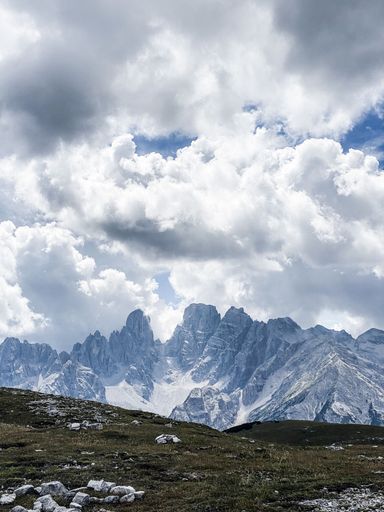 A vertical shot of a dry hillside in the Dolomites on a bright sunny day with fluffy clouds in the sky