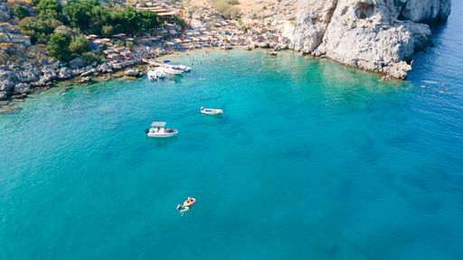 An aerial view of a rocky bay with ships on a sunny day