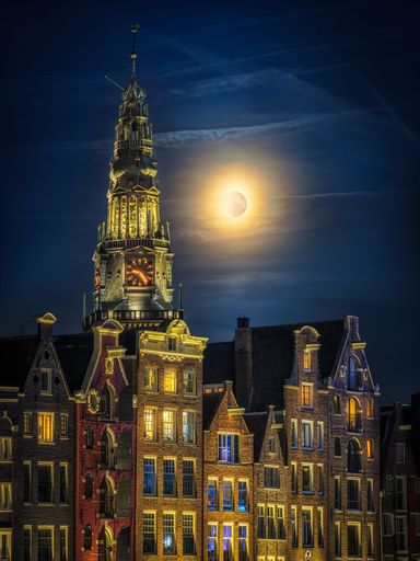A vertical shot of an old church of Damrak and moonlight in the background in Amsterdam