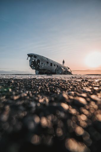 A vertical silhouette of a person standing on solheimasandur plane wreck in Iceland against the sky at sunset