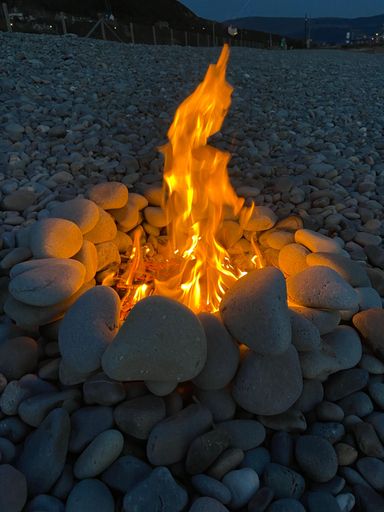 A fire pit on a rocky beach at night